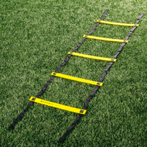 Yellow and black soccer agility ladder laid out flat on a green grass field, used for speed and footwork training.