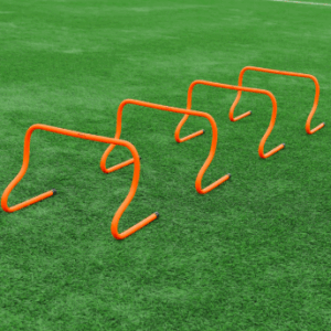 Set of four orange footwork training hurdles standing on a green artificial turf field, used for plyometric and footwork training.
